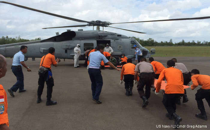 Indonesian authorities at Iskander Air Base approach an MH-60R Seahawk from HSM- 35 to retrieve victims recovered by USS Sampson (DDG-102).